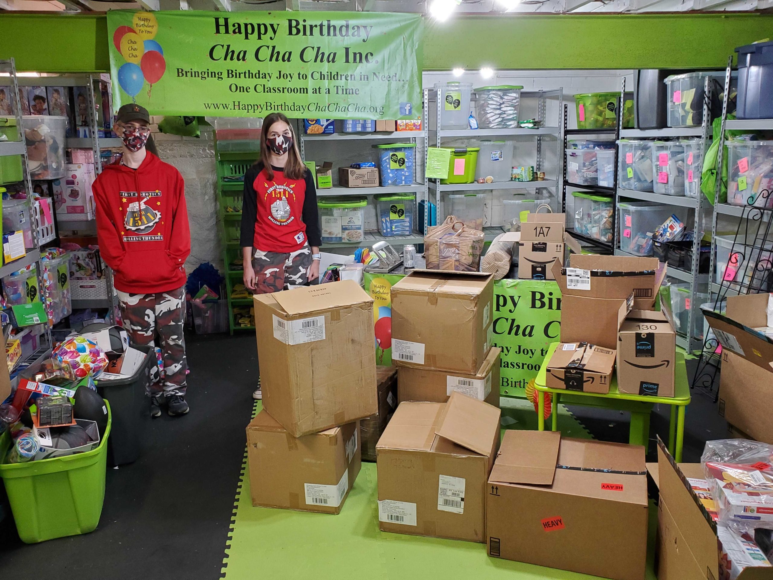 2 students with boxes at Happy Birthday Cha Cha Cha storage room