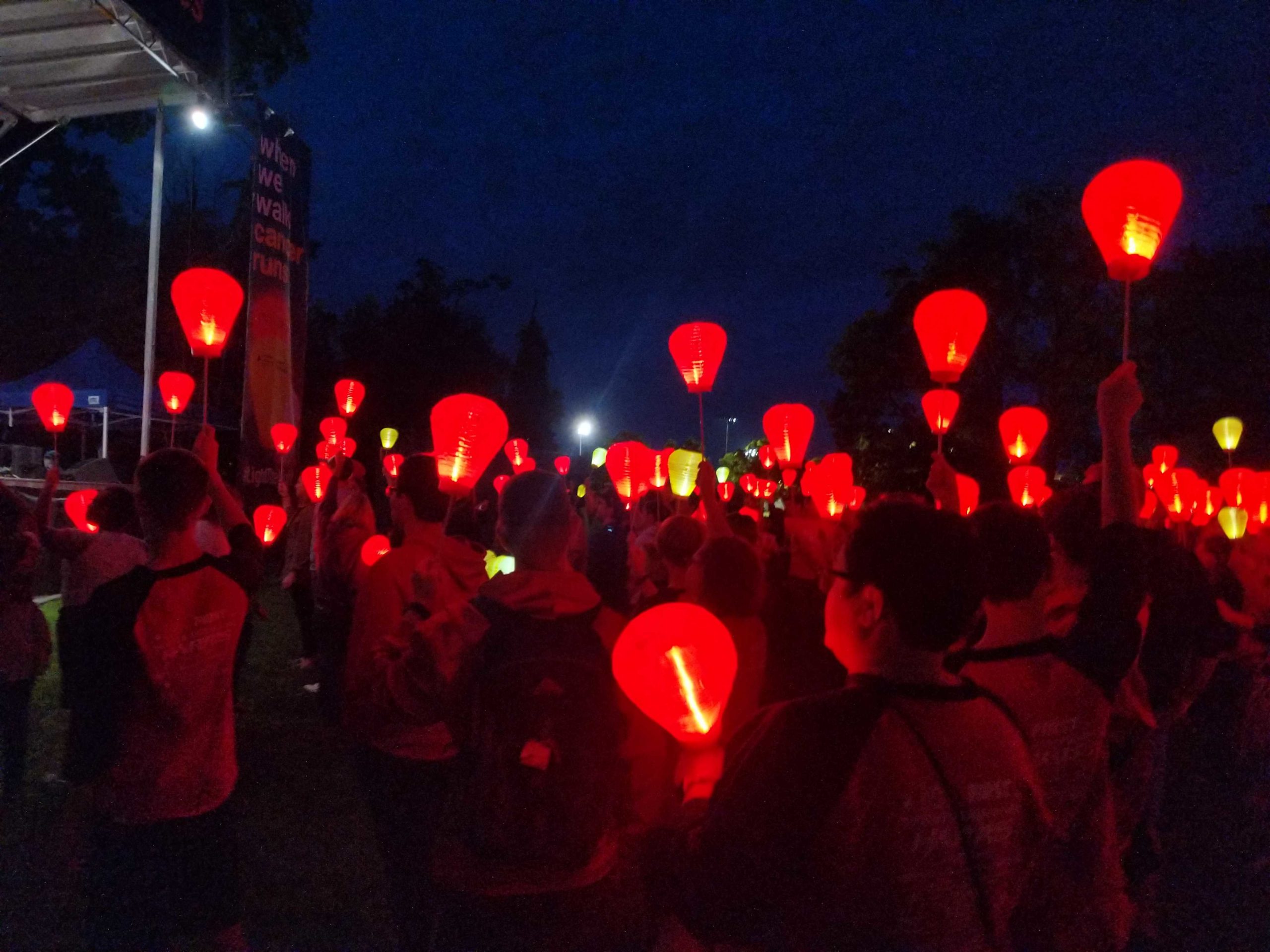 Crowd at night holding red and yellow lighted lanterns at Light the Night Walk