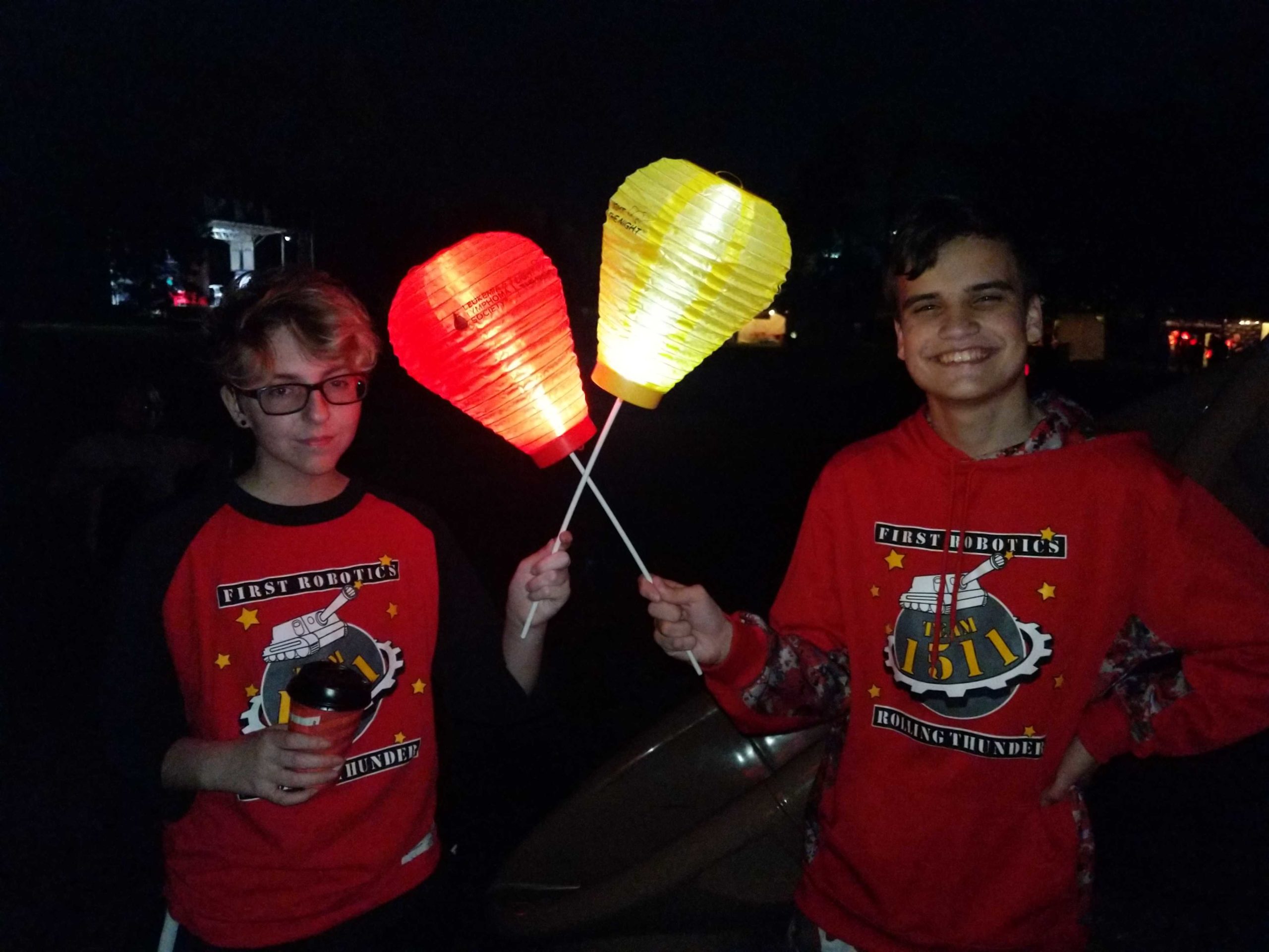 2 students at night holding lighted colored lanterns at the Light the Night walk