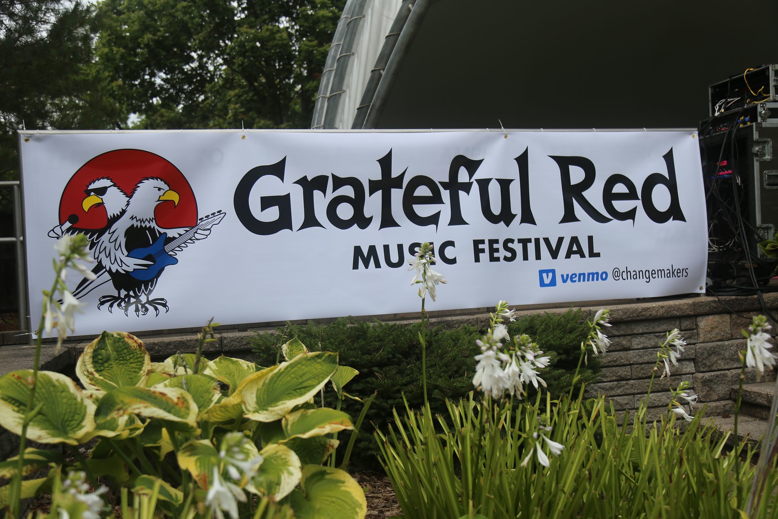 White Banner hanging on fence with Grateful Red Music Festival words and Logo