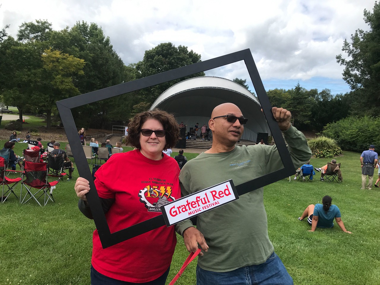 2 people holding a frame around their heads that says Grateful Red Music Festival