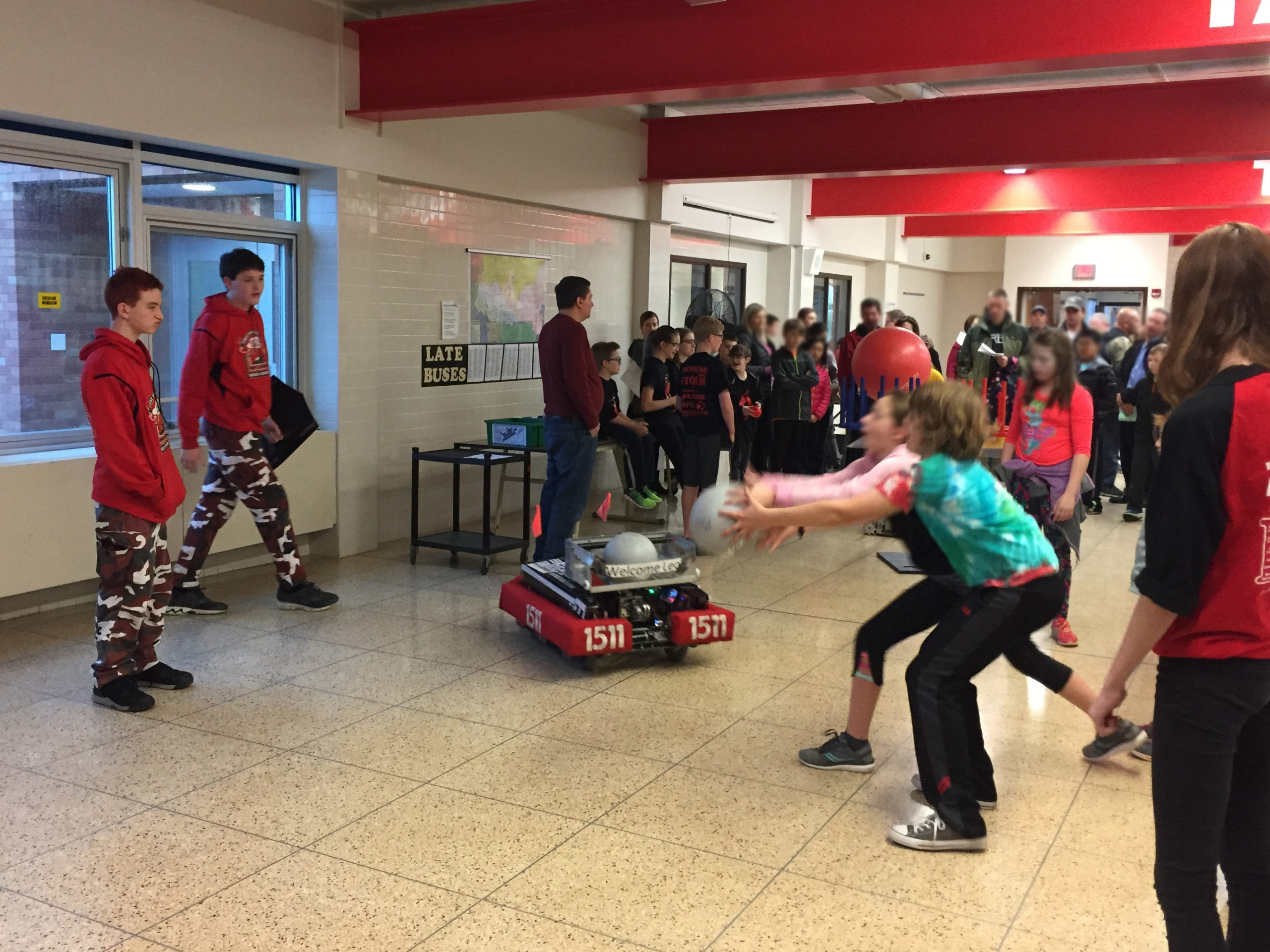 2 youth trying to catch a ball tossed by robot at Bay Trail Middle School FIRST EXPO Night