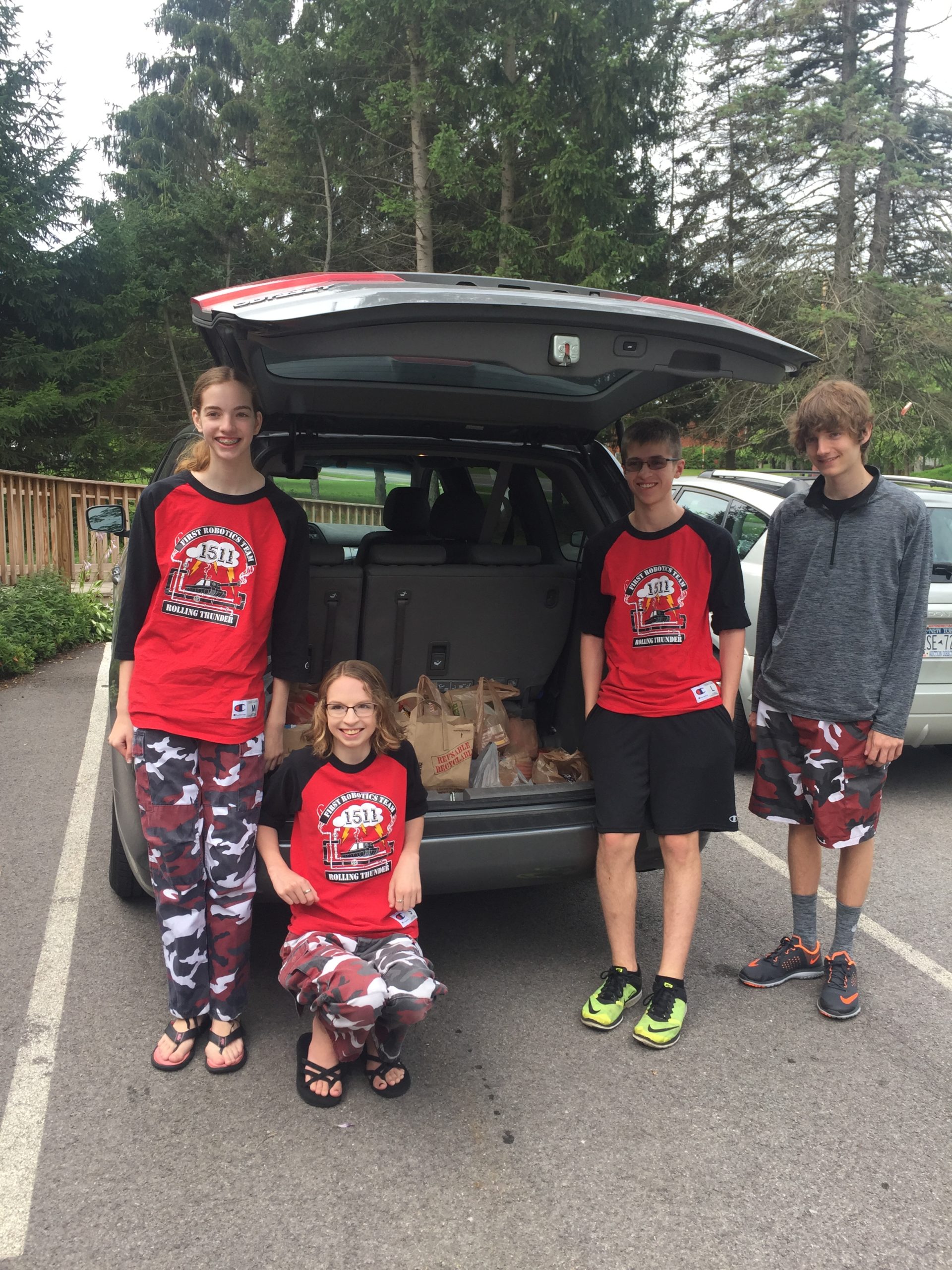 4 team members standing in front of car truck filled with donations for Penfield Ecumenical Food Shelf