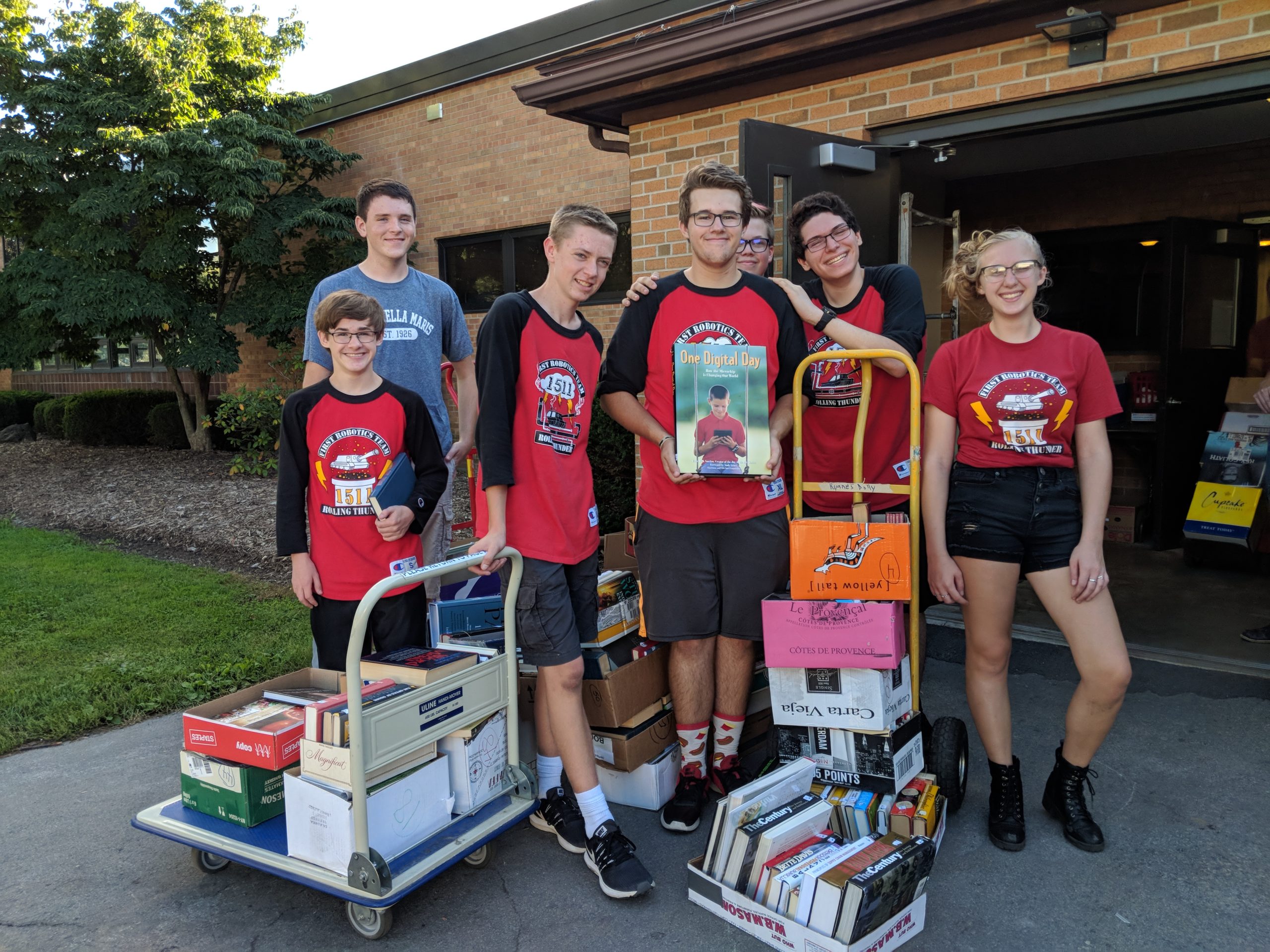 Team members with boxes of books on carts helping cleanup at the Penfield Library Booksale