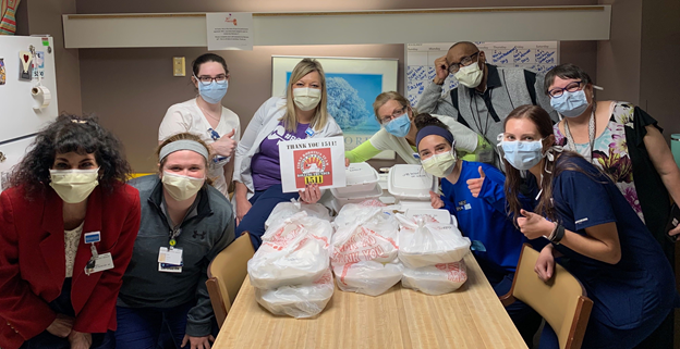 Healthcare workers in a room wearing masks in with take our food donated by Team 1511