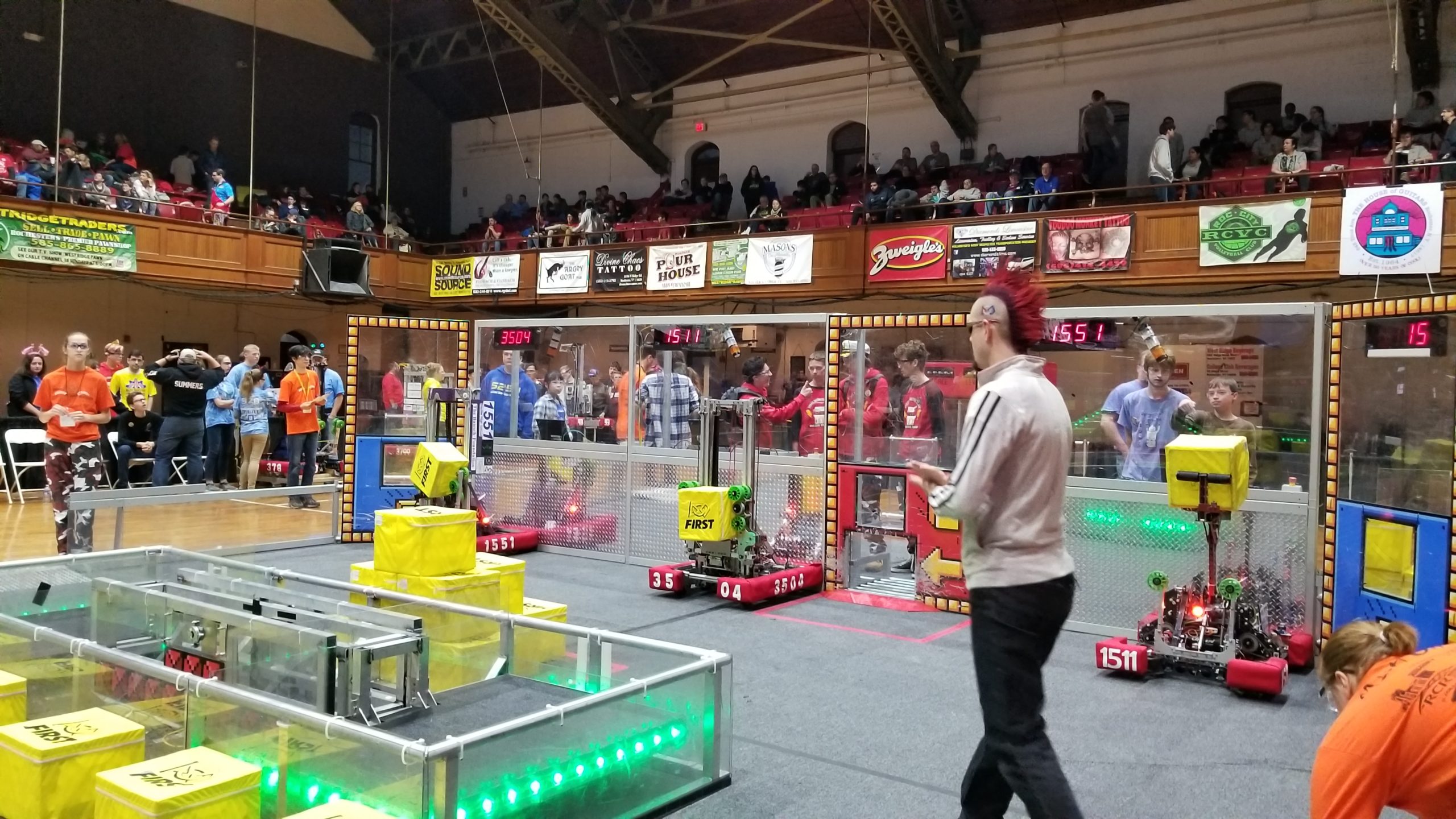 Photo of announcer on a playing field with robotics at Rochester Ruckus