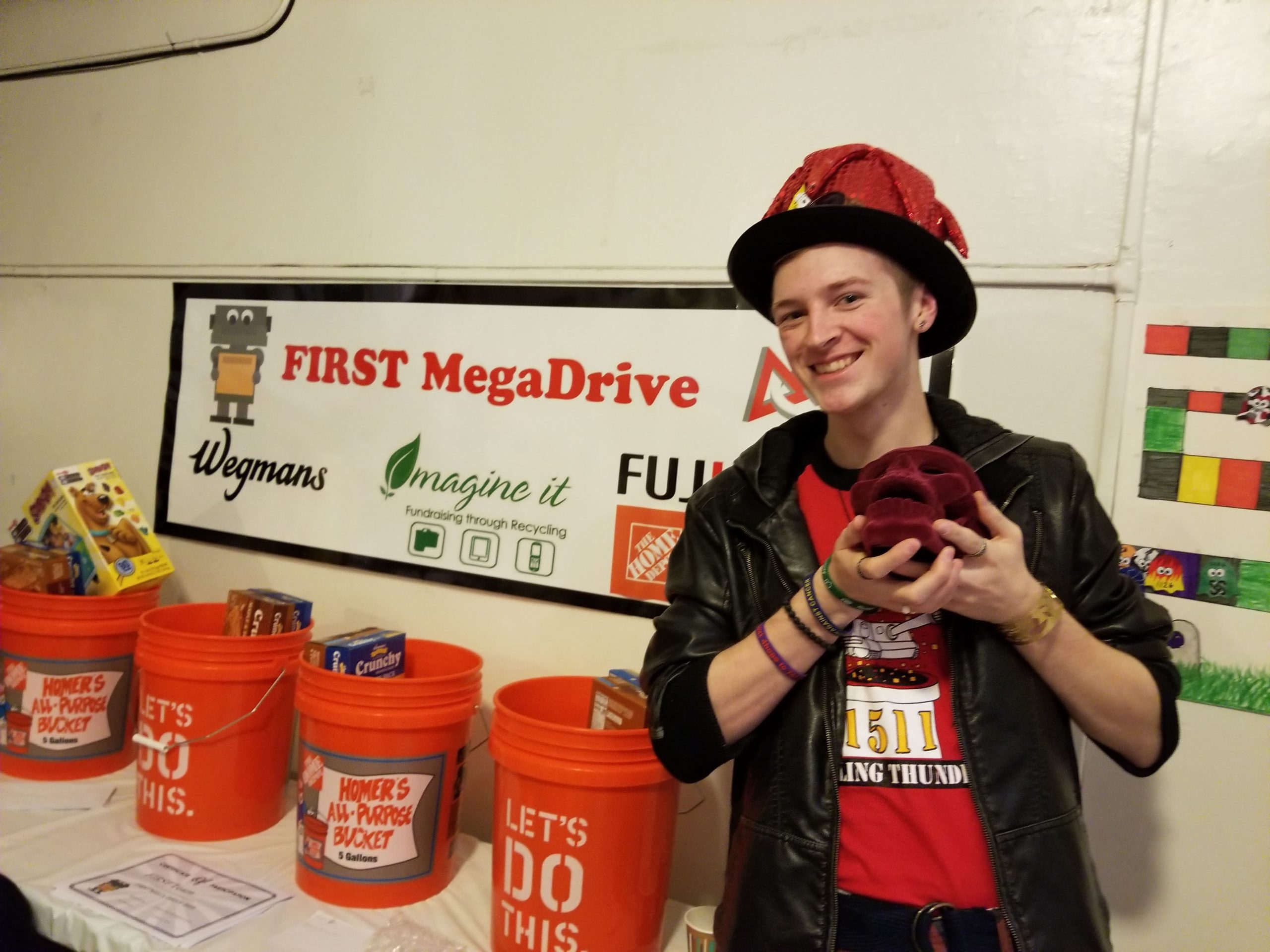 Photo of team member in front of Mega Drive sign with collection buckets at Rochester Ruckus