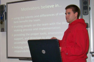 eam mentor presenting in front of screen that says motivators believe in...