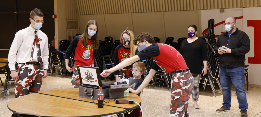 Team members showing a child how to work the robot controls
